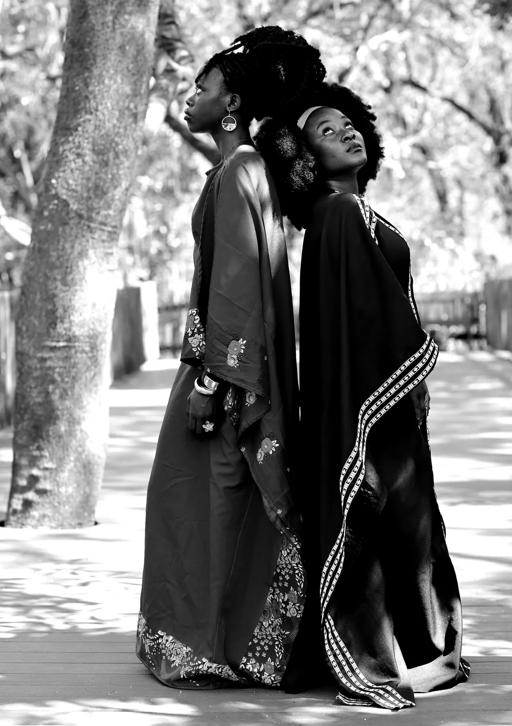 Two women in Venda minwenda stand under a tree.