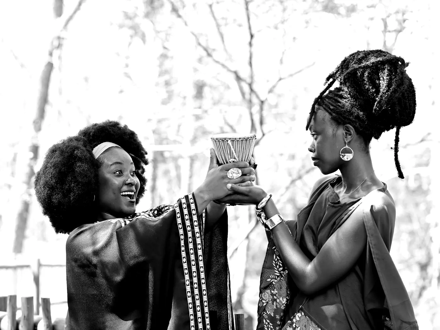 Two women, one in black and one in blue, pass a small drum between them.