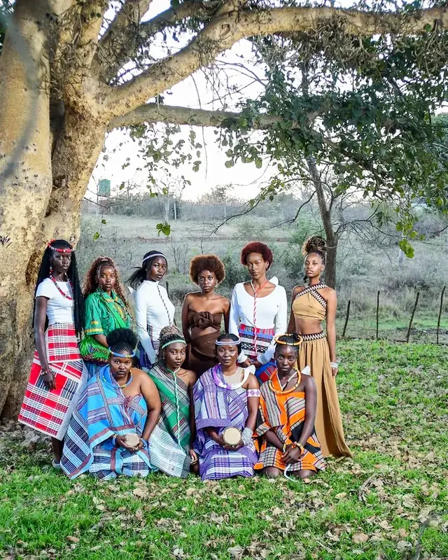 A group gathered in the shade of a great tree.
